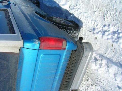 1979 Ford Bronco - Rear view of a blue SUV with a spare tire, partially buried in snow.