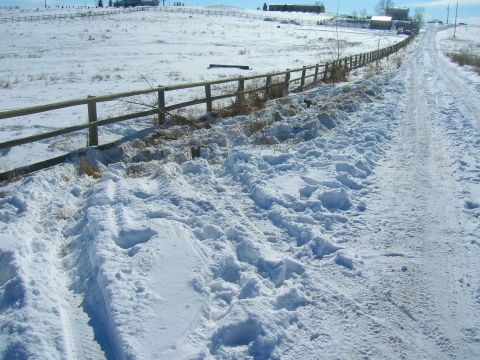 1979 Ford Bronco - A rural landscape covered in snow, with tire tracks visible on the road.