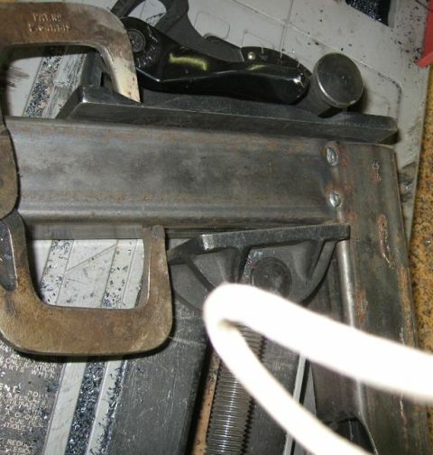 1990 Ford Bronco - A close-up view of a metal component secured by clamps, with some text visible on a label below.