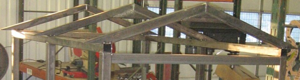 Metal roof truss structure under construction, with visible welding and support beams