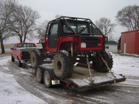 1992 Ford Bronco - A heavily modified off-road vehicle is loaded onto a trailer, ready for transport in a snowy landscape.