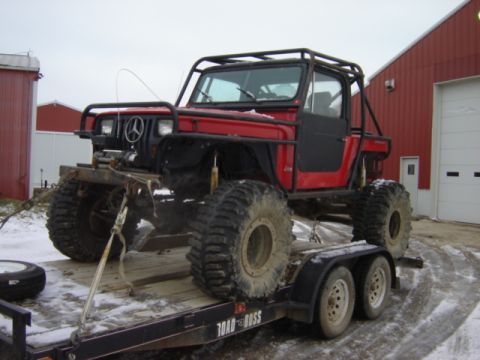 1992 Ford Bronco - This heavily modified off-road vehicle, a roll cage and oversized tires, is loaded onto a trailer.