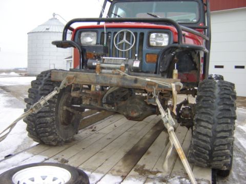 1992 Ford Bronco - Front view of a heavily modified Jeep with a winch and large off-road tires. A Mercedes-Benz emblem is visible on the grille.