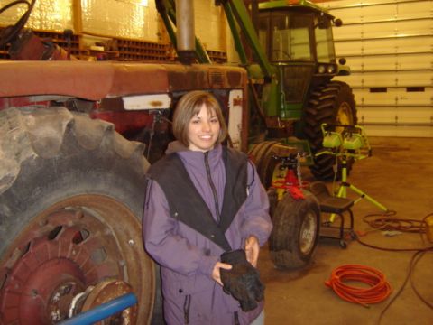 1992 Ford Bronco - Woman poses with two tractors in a garage setting.