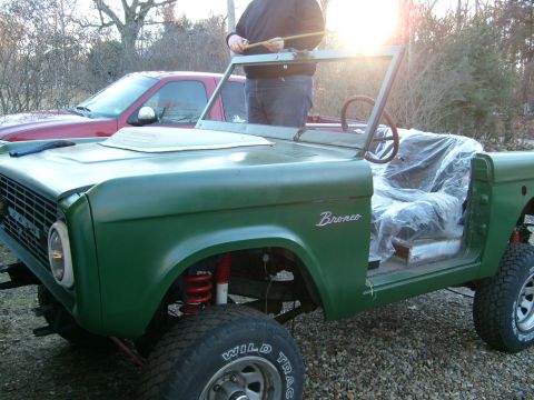 1974 Ford Bronco - A green Ford Bronco is shown with its interior covered in plastic, and a person is taking measurements.