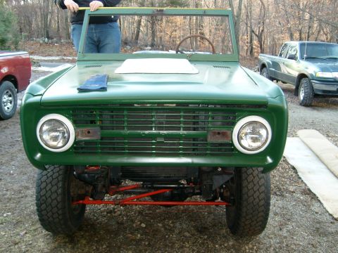 1974 Ford Bronco - A green 1974 Ford Bronco is shown from the front, with a person measuring its windshield frame.