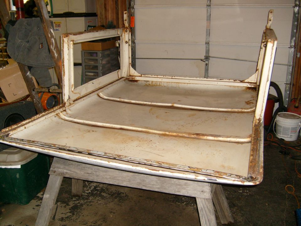 White Ford Bronco hardtop assembly, showing rust and wear, resting on sawhorses in a garage