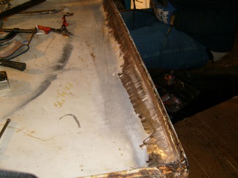 1974 Ford Bronco - A person works on a corroded metal panel, with tools scattered around the workspace.