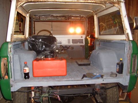1974 Ford Bronco - The interior of a 1974 Ford Bronco shows an orange fuel can and a plastic-wrapped seat, suggesting it is undergoing restoration.
