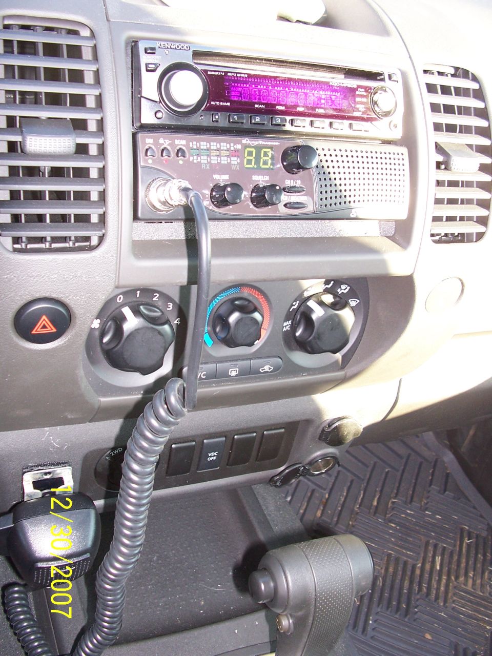 Vehicle center dash with Kenwood stereo, CB radio, HVAC knobs and coiled CB mic cable
