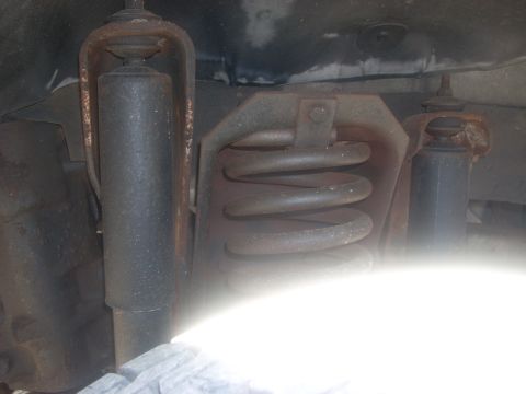 1992 Ford Bronco - This image shows the front suspension system of a vehicle, including a shock absorber and coil spring.