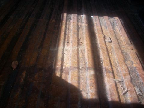 1992 Ford Bronco - The ribbed surface of a truck bed shows signs of rust and is partially covered by shadows.
