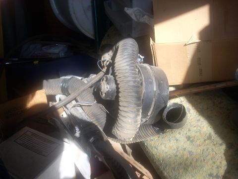 1992 Ford Bronco - A close-up view of a vehicle's HVAC blower motor assembly, surrounded by storage items.