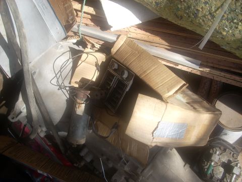 1992 Ford Bronco - Various car parts, including dashboard vents and a motor, are stored haphazardly with boxes and scrap wood.