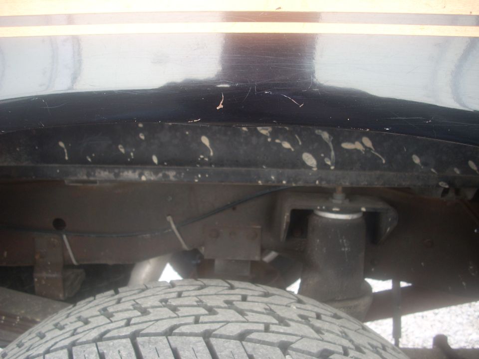 Rear suspension and tire of a vehicle with black paint and a yellow stripe