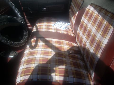 1992 Ford Bronco - The interior of the vehicle features plaid seat covers and a license plate on the passenger seat.