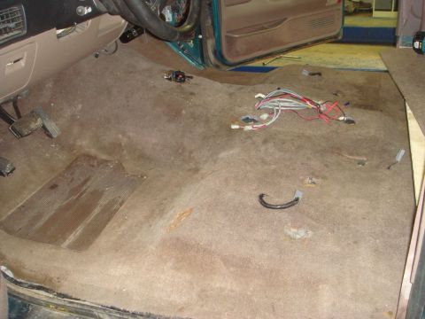 1996 Ford Bronco - Interior floor of a 1996 Ford Bronco, carpet removed, revealing pedals, wiring, and rust.