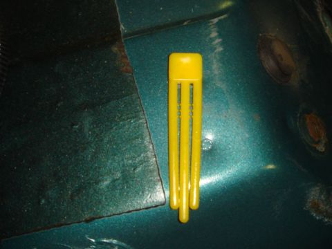 1996 Ford Bronco - A yellow plastic clip rests on teal painted metal, showing signs of rust and wear.