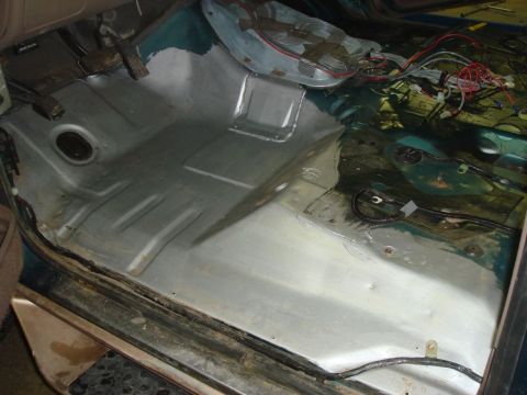 1996 Ford Bronco - The interior floor of a vehicle shows exposed metal, wiring, and signs of repair work.