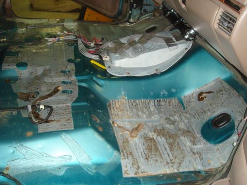 1996 Ford Bronco - Vehicle interior floor showing rust and exposed metal, with wiring present.
