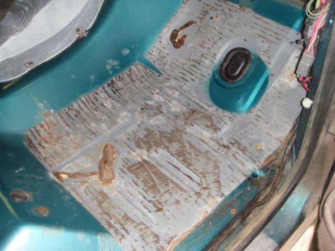 1996 Ford Bronco - The interior floor of a vehicle shows signs of wear, rust, and exposed wiring near the door sill.