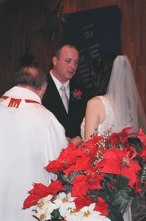 1984 Ford Bronco - A wedding ceremony is taking place, with a couple exchanging vows in front of an officiant, surrounded by festive poinsettias.