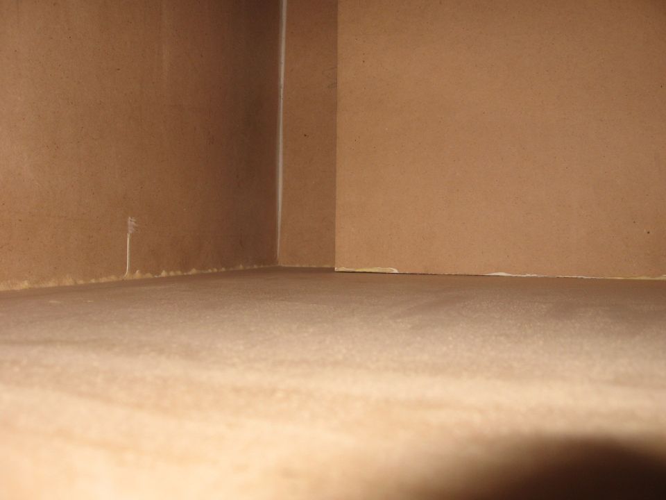 Interior corner of a room with brown walls and floor, showing a seam where walls meet
