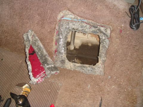 1992 Ford Bronco - A section of carpeted floor has been cut out, revealing mechanical components beneath.