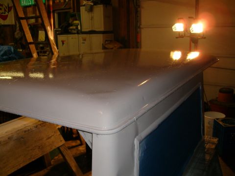 1974 Ford Bronco - The top of a vehicle is shown in a garage setting, reflecting light from overhead lamps.