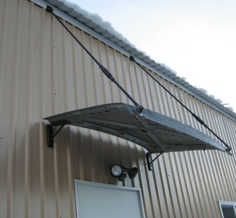 1986 Ford Ranger - A car hood has been repurposed as an awning above a doorway on a corrugated metal building.
