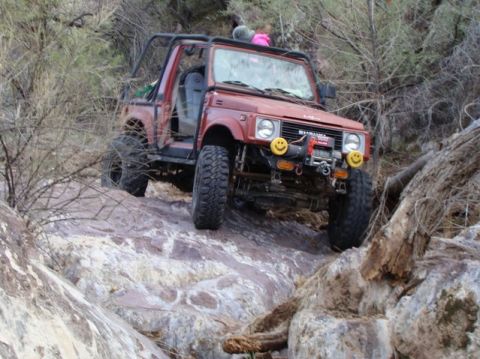 1987 Suzuki Samurai - This 1987 Suzuki Samurai navigates a rocky trail, equipped with a winch and distinctive smiley face fog lights.