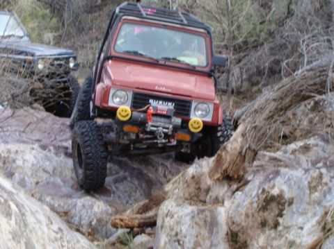 1987 Suzuki Samurai - Suzuki Samurai navigating a difficult rocky trail with another vehicle in the background.