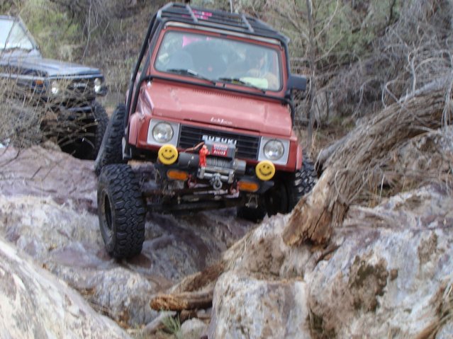 1987 Suzuki Samurai climbing rocky terrain, another dark SUV behind it