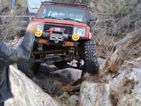 1987 Suzuki Samurai - A red Suzuki Samurai navigates a rocky trail, with another vehicle visible in the background.