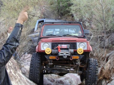 1987 Suzuki Samurai - A red 1987 Suzuki Samurai navigates a rocky trail, with another vehicle behind it.