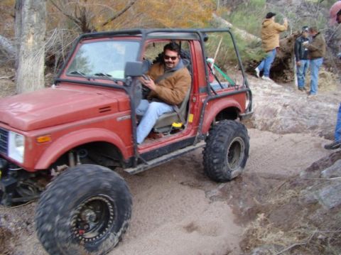 1987 Suzuki Samurai - A red 1987 Suzuki Samurai navigates a sandy, off-road trail with a driver and passengers.