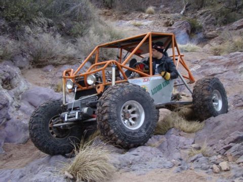 1987 Suzuki Samurai - A custom off-road buggy navigates a rocky trail with a driver at the wheel.