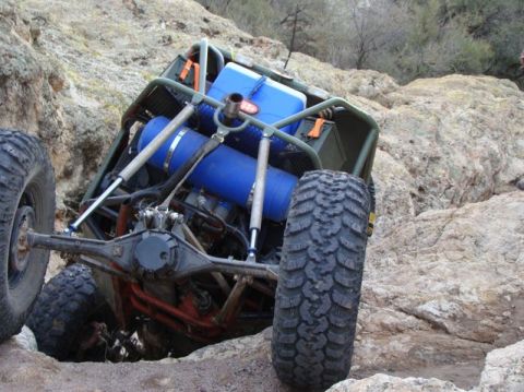 1987 Suzuki Samurai - Modified buggy with large blue tanks navigates rocky terrain.