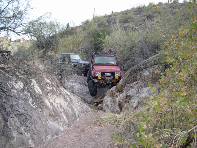 Red Suzuki Samurai and black Jeep navigating a rocky trail