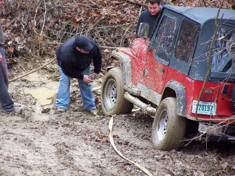 2002 Ford Sport Trac - Red Jeep Wrangler stuck in mud, two people are attempting to get it unstuck. Indiana plate 2U157.