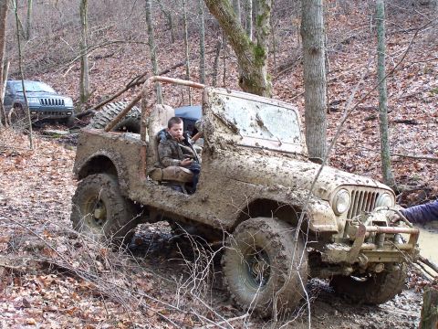 2002 Ford Sport Trac - A muddy Jeep CJ navigates a wooded trail with another SUV visible in the background.