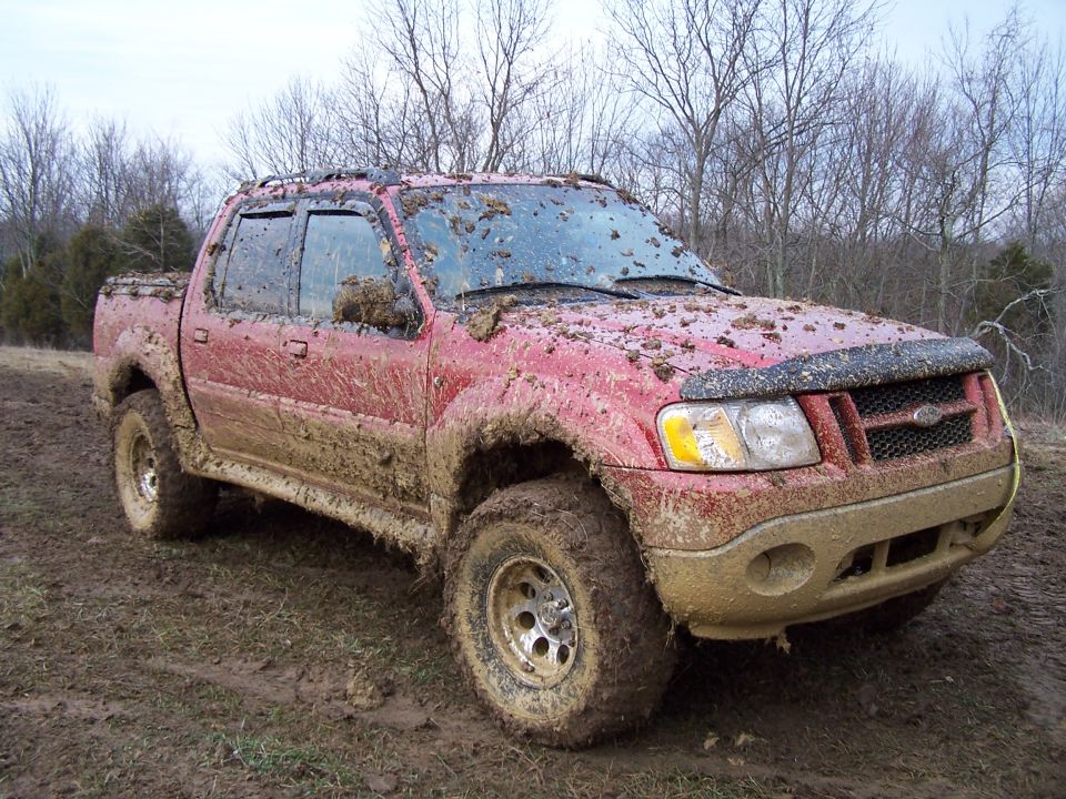 Red 2002 Ford Sport Trac covered in mud, front quarter view