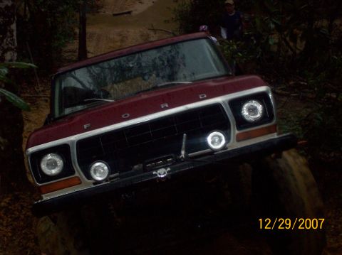 1978 Ford Bronco - A maroon 1978 Ford Bronco navigates rough terrain on an off-road trail.