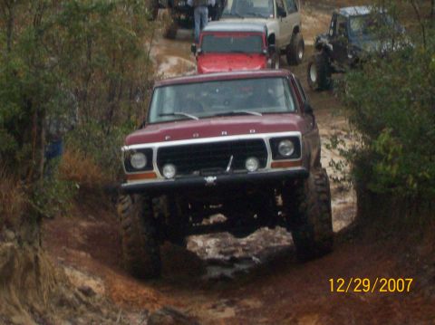1978 Ford Bronco - A maroon 1978 Ford Bronco navigates a muddy off-road course with other vehicles visible in the background.