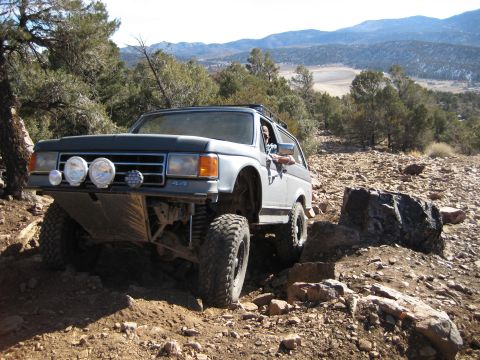 1996 Ford Bronco - This modified 1987 Ford Bronco is navigating a challenging rocky trail in a mountainous, arid landscape.