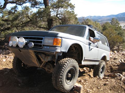 1996 Ford Bronco - This modified Ford Bronco navigates a challenging off-road path with large tires and a custom bumper.