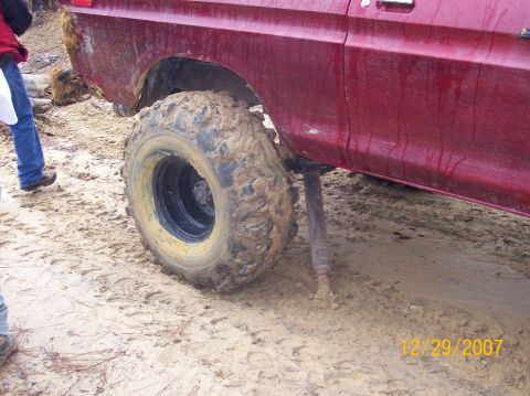 1978 Ford Bronco - A red 1978 Ford Bronco is stuck in the mud, showing its large tires and the muddy terrain.