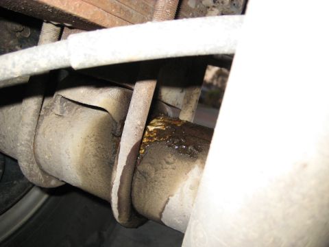 1996 Ford Bronco - Detail of a vehicle's rear axle and suspension system, showing signs of grease and a leak from a component.