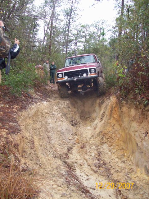 1978 Ford Bronco - A red 1978 Ford Bronco tackles a challenging off-road course, demonstrating its capability on rough terrain.