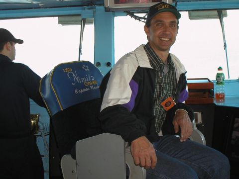 1989 Ford F-250 - A man smiles while sitting in the captain's chair on the bridge of the USS Nimitz.